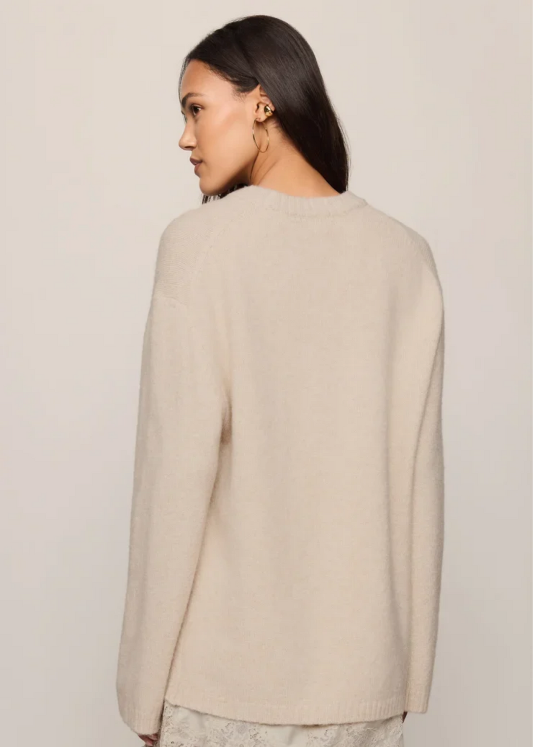 Woman wearing a frosted pearl sweater that is long sleeved.