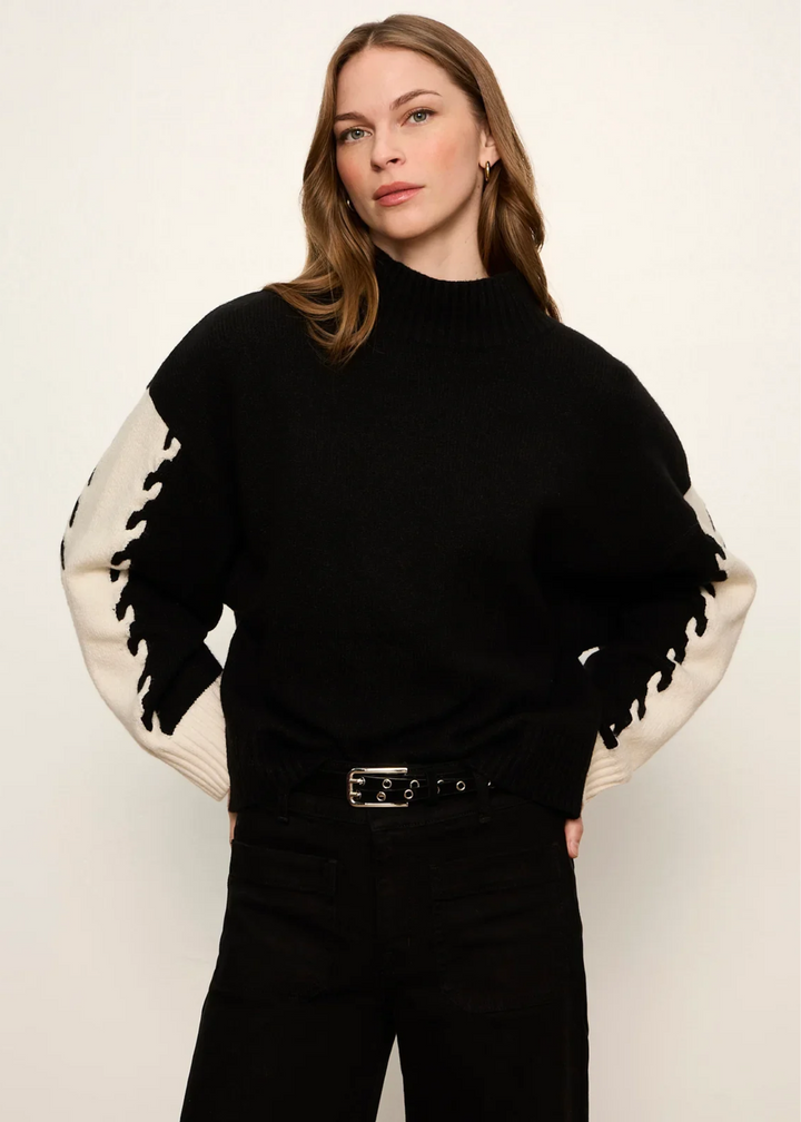 Woman wearing black and bone color block sweater.