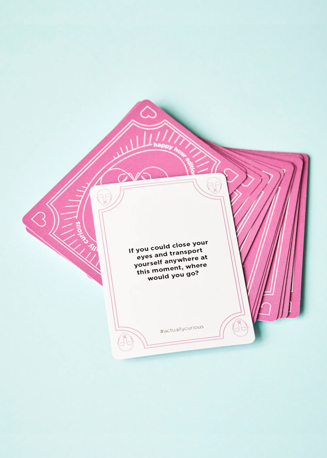 A white card with a question laying on top of pink cards