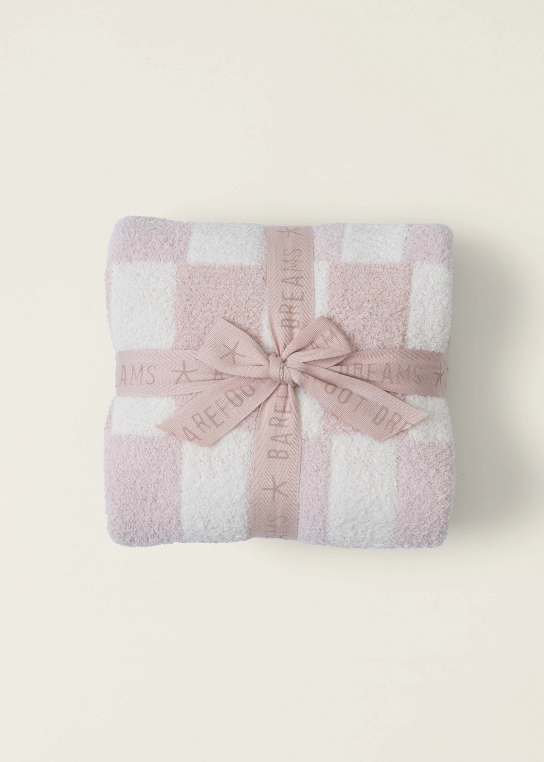 A pink and white checked blanket folded with a pink ribbon laying on a white background