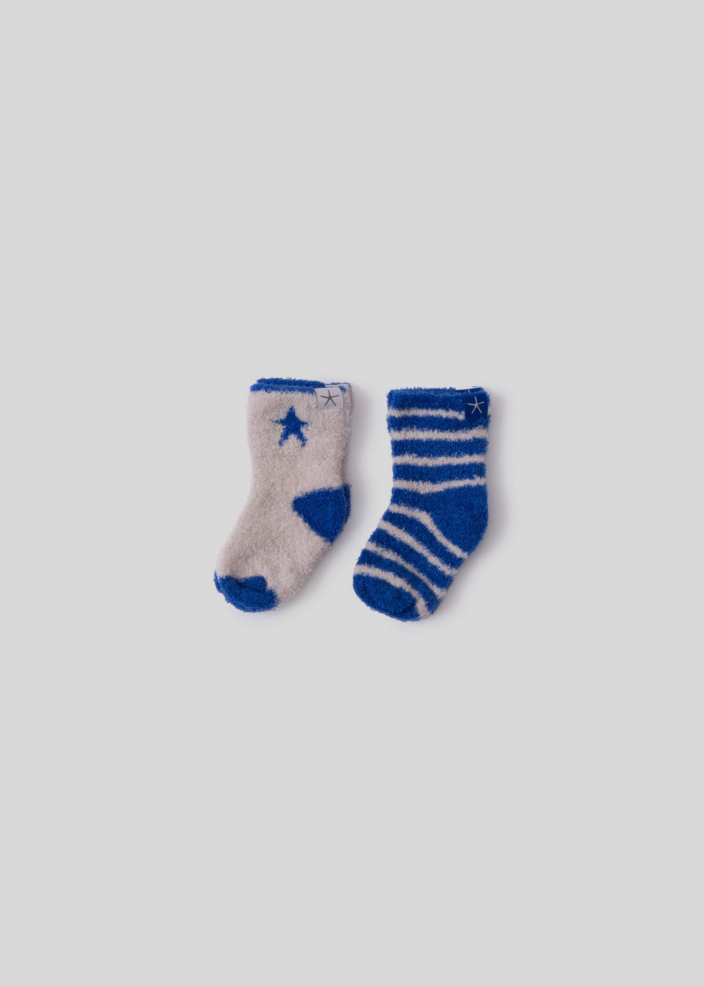 A white sock with cobalt blue trim and a star next to a cobalt blue sock with white stripes both laying on a white background