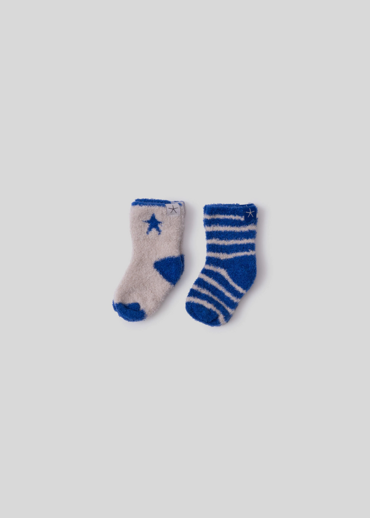 A white sock with cobalt blue trim and a star next to a cobalt blue sock with white stripes both laying on a white background