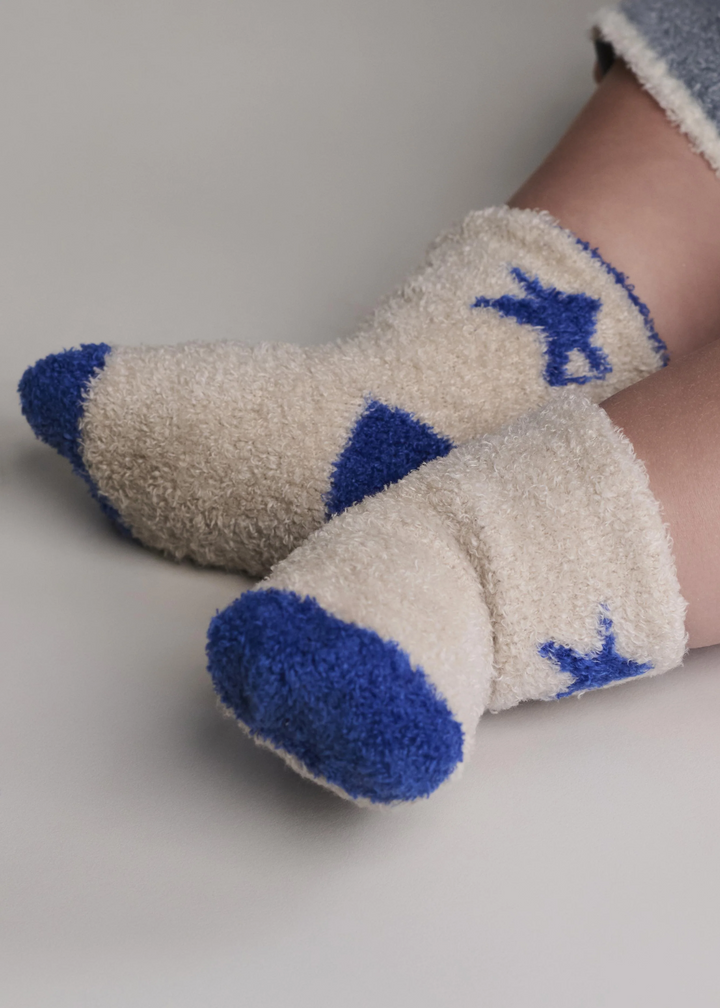Baby wearing white socks with cobalt blue stars, toes, and heels