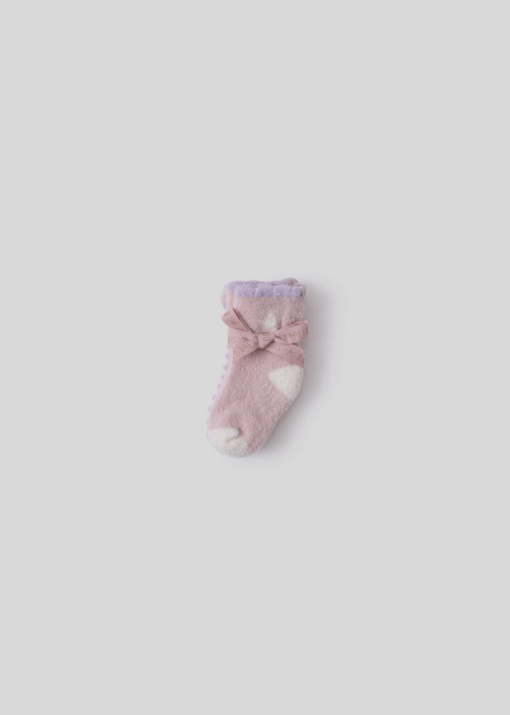 Pink and purple baby socks tied together laying on a white background