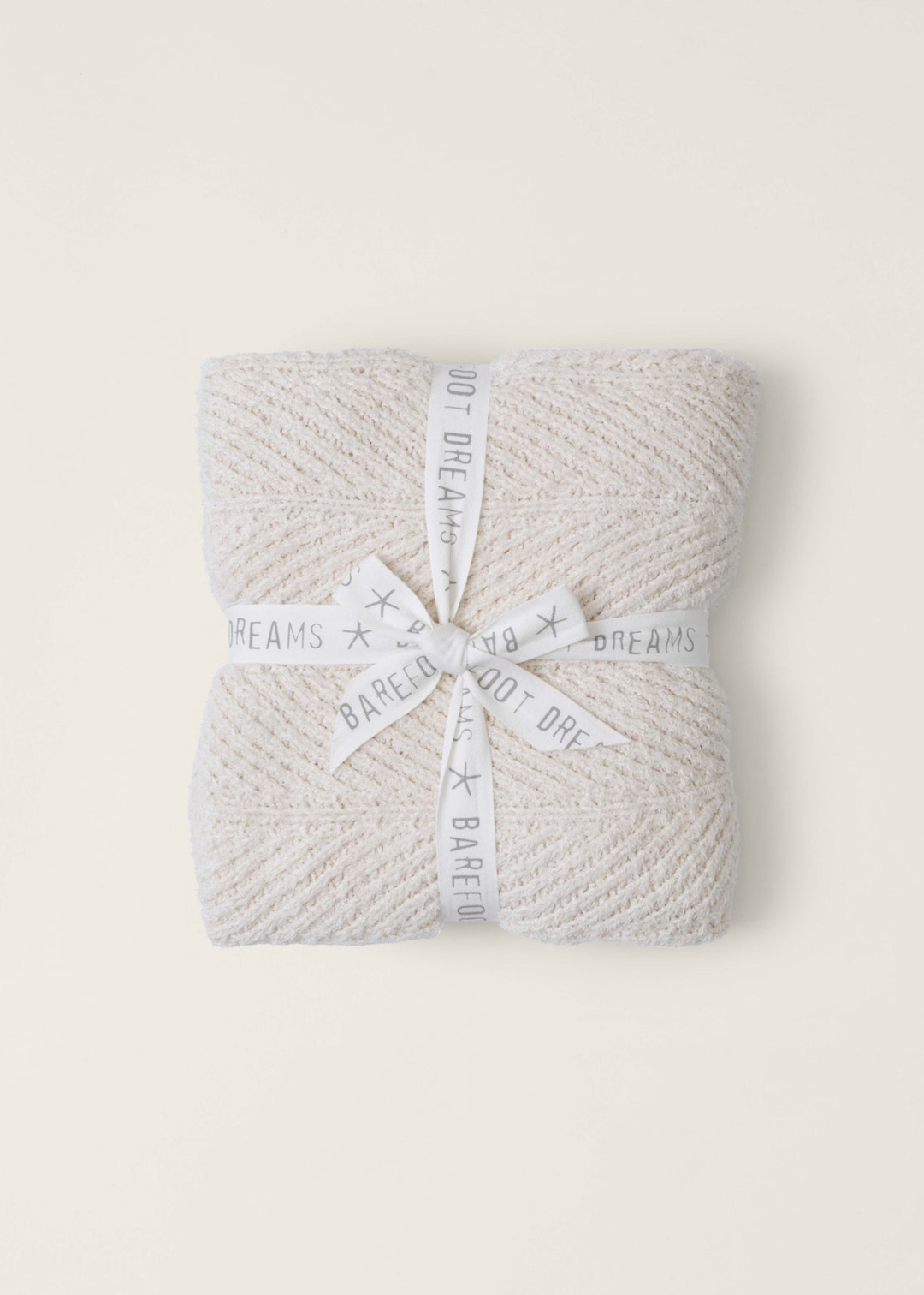 Cream blanket folded and wrapped with a white ribbon on a white background
