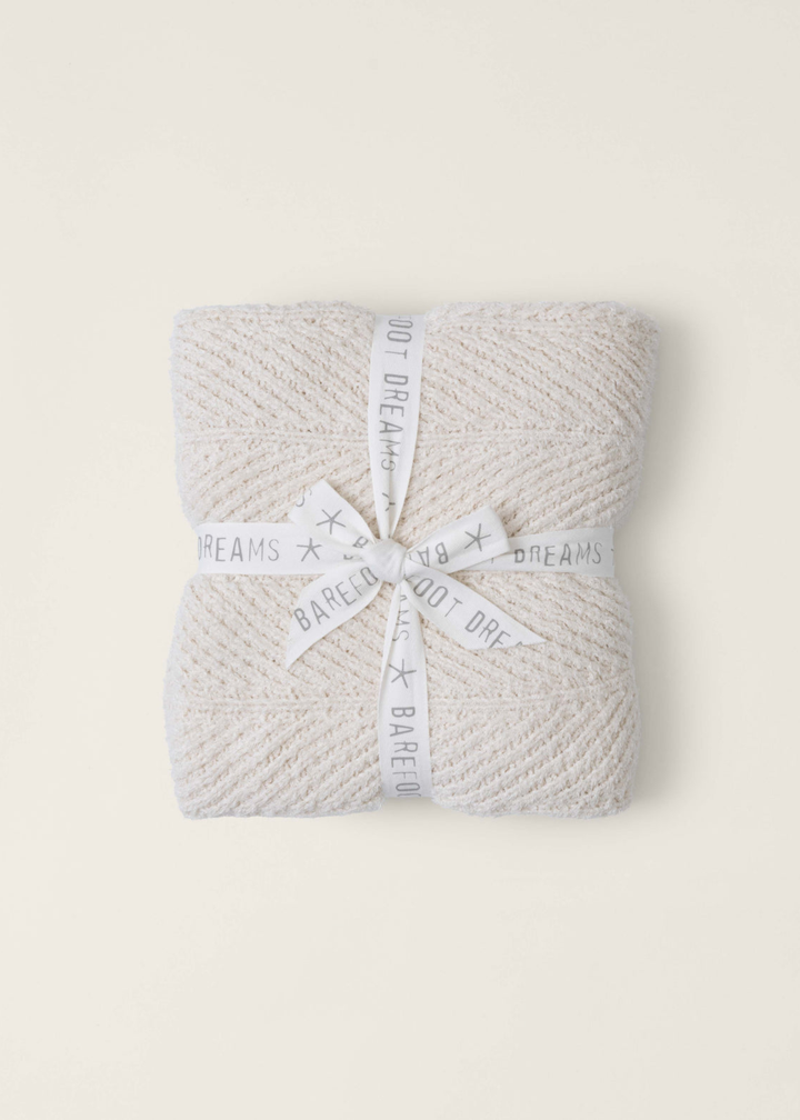Cream blanket folded and wrapped with a white ribbon on a white background