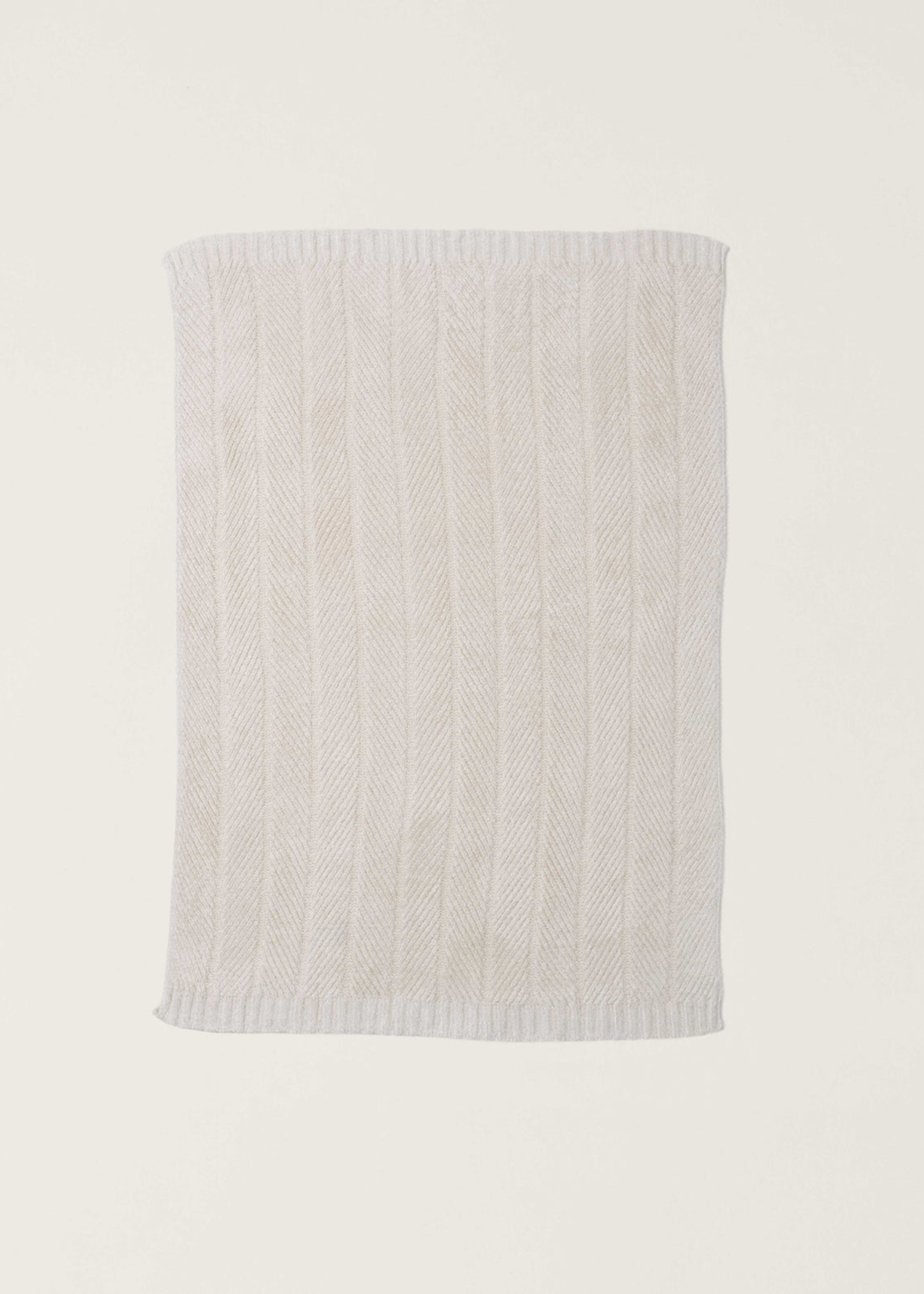 Cream blanket with a herringbone pattern laid on a white background