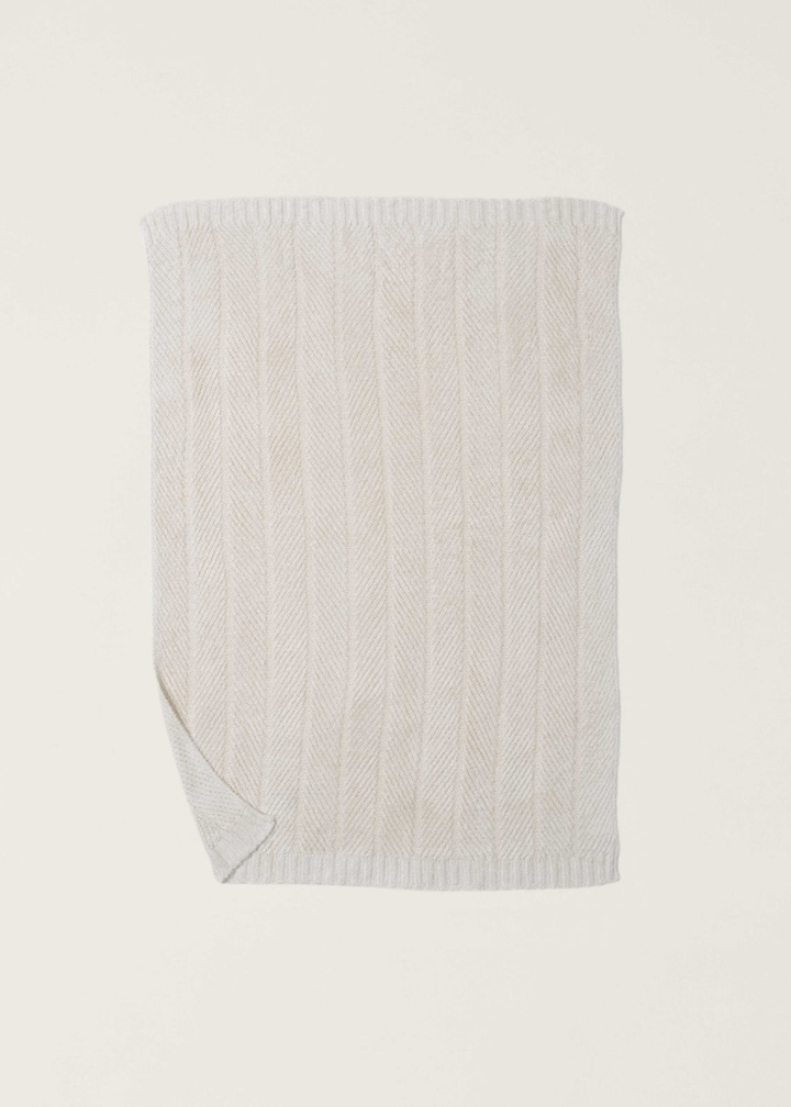 Cream blanket with a herringbone pattern and the bottom left corner folded laid on a white background