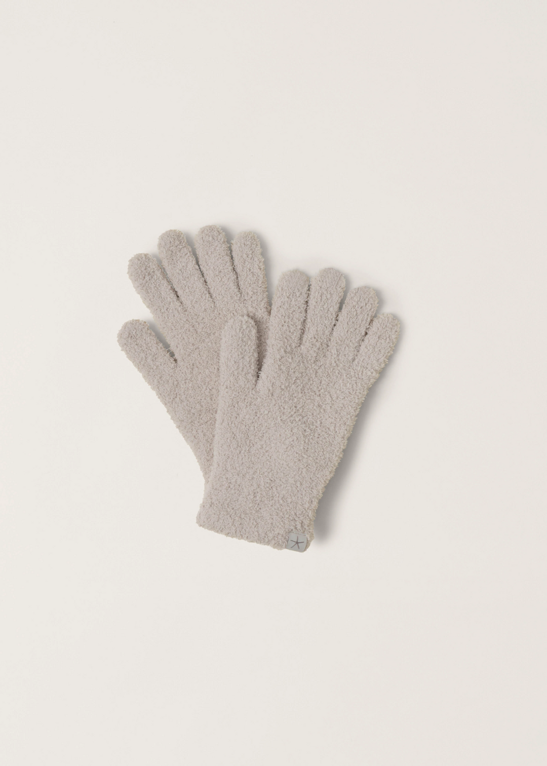 Light grey fuzzy gloves laying on a white background