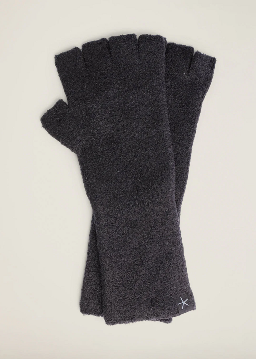 Charcoal grey fuzzy fingerless gloves laying on a white background