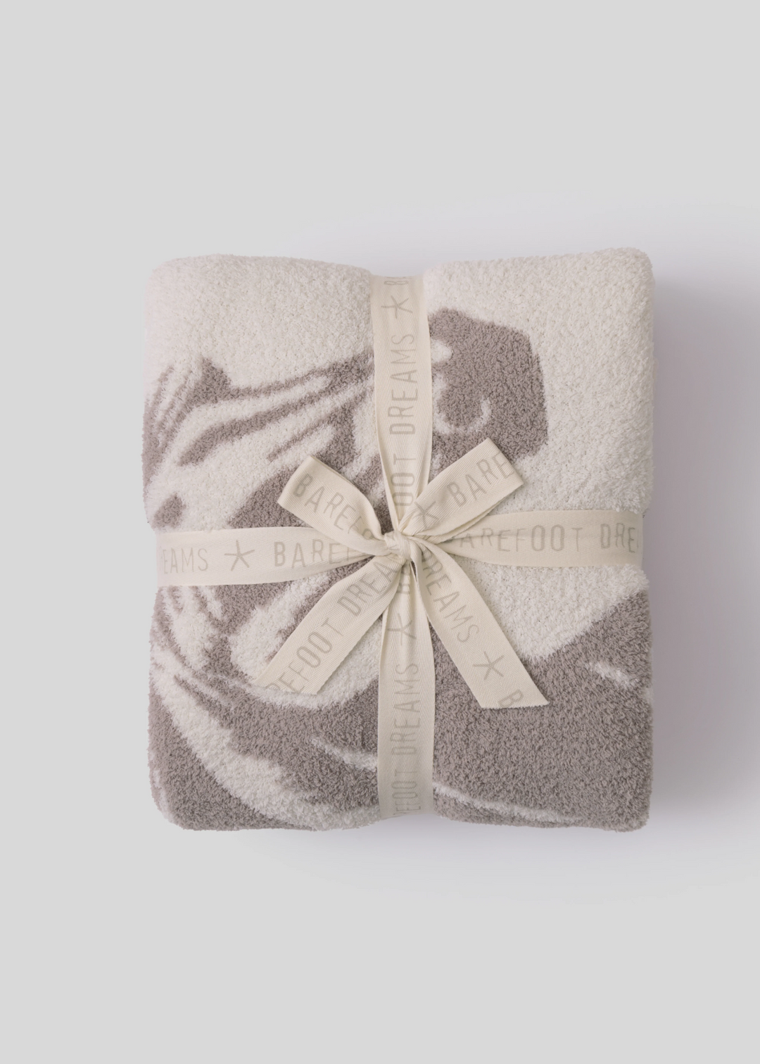 Folded blanket with a cream bow sitting on a white background