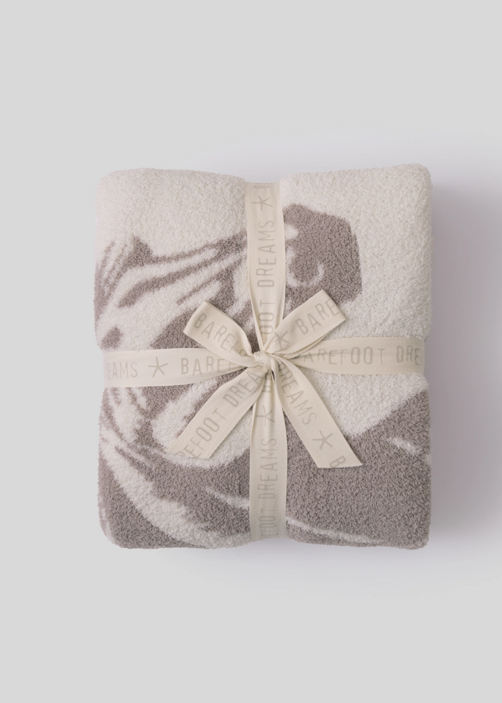 Folded blanket with a cream bow sitting on a white background