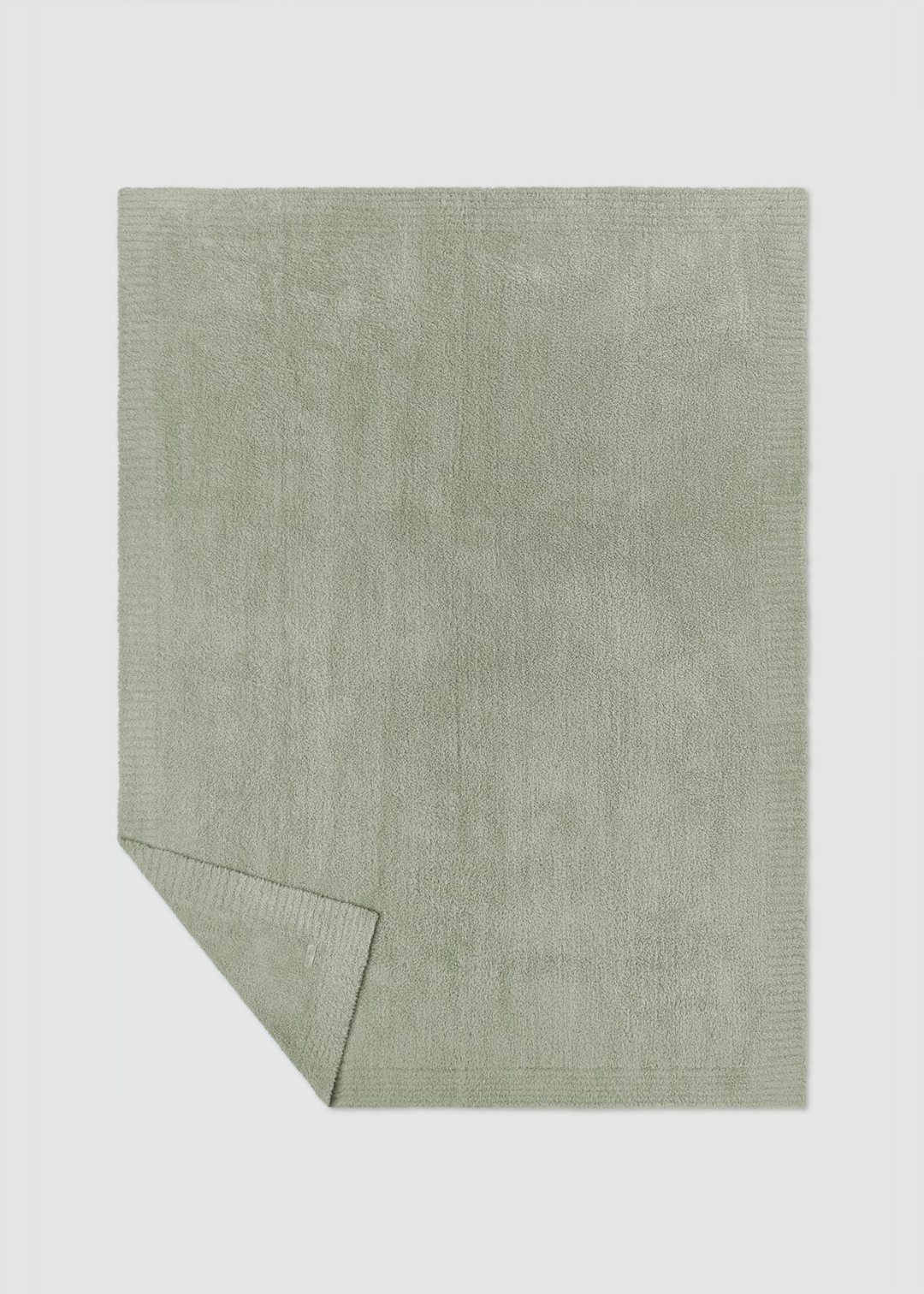Green blanket laying on a gray background with a corner folded