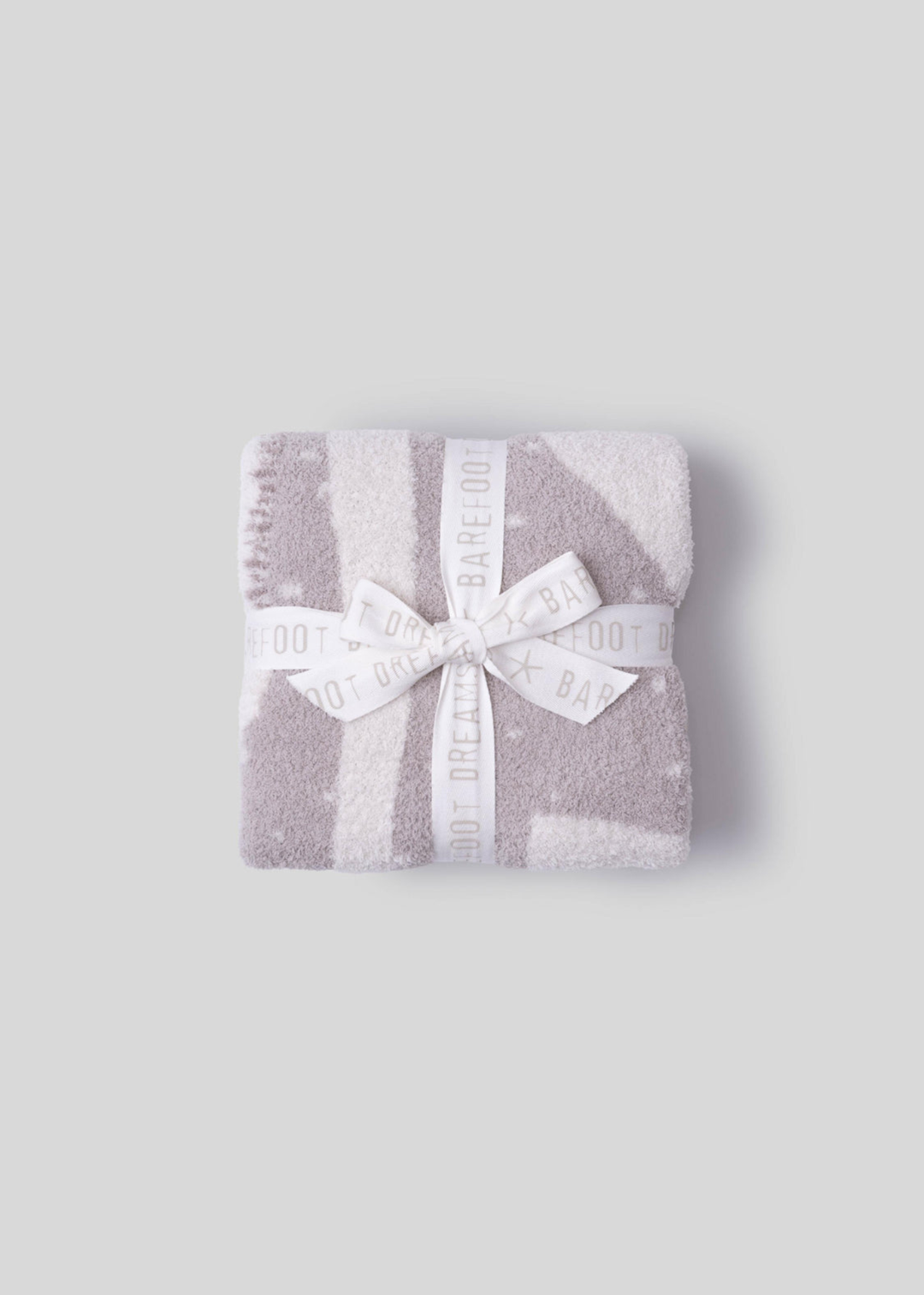 Folded pink and cream blanket with a white bow on a white background