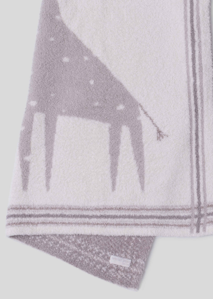 Close up of a pink and cream blanket with a giraffe graphic and a striped border folded in half on a white background