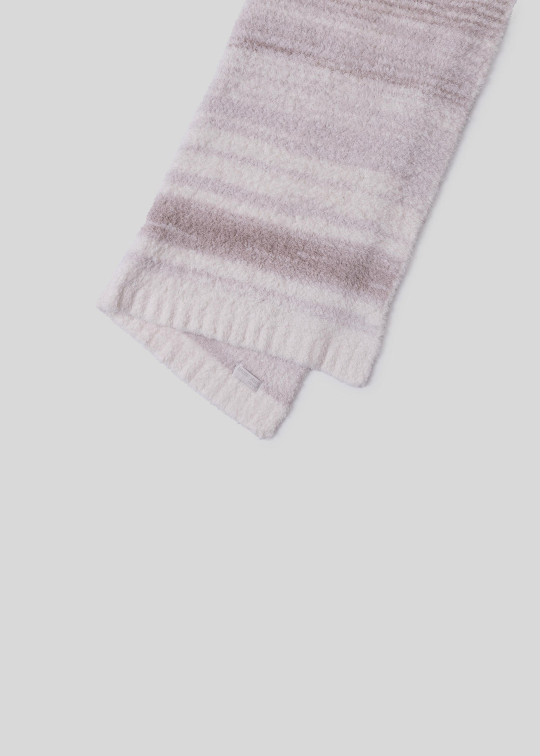 Pink and cream striped blanket folded in half laying on a white background