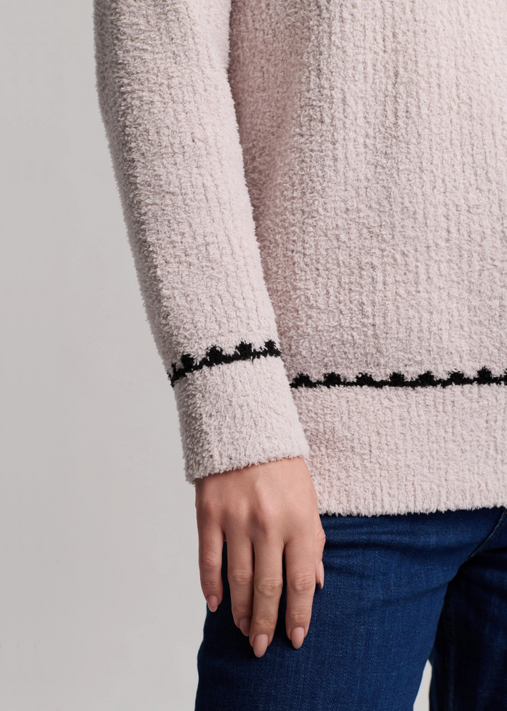 Close up of a woman wearing acream ribbed sweater with black trim
