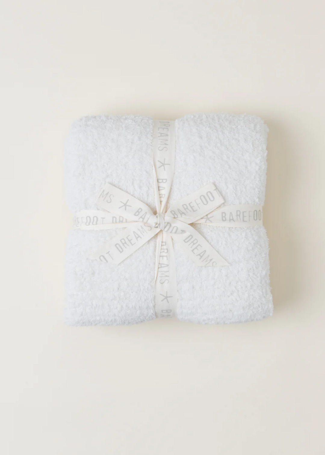 A cream blanket folded and laying on a white background