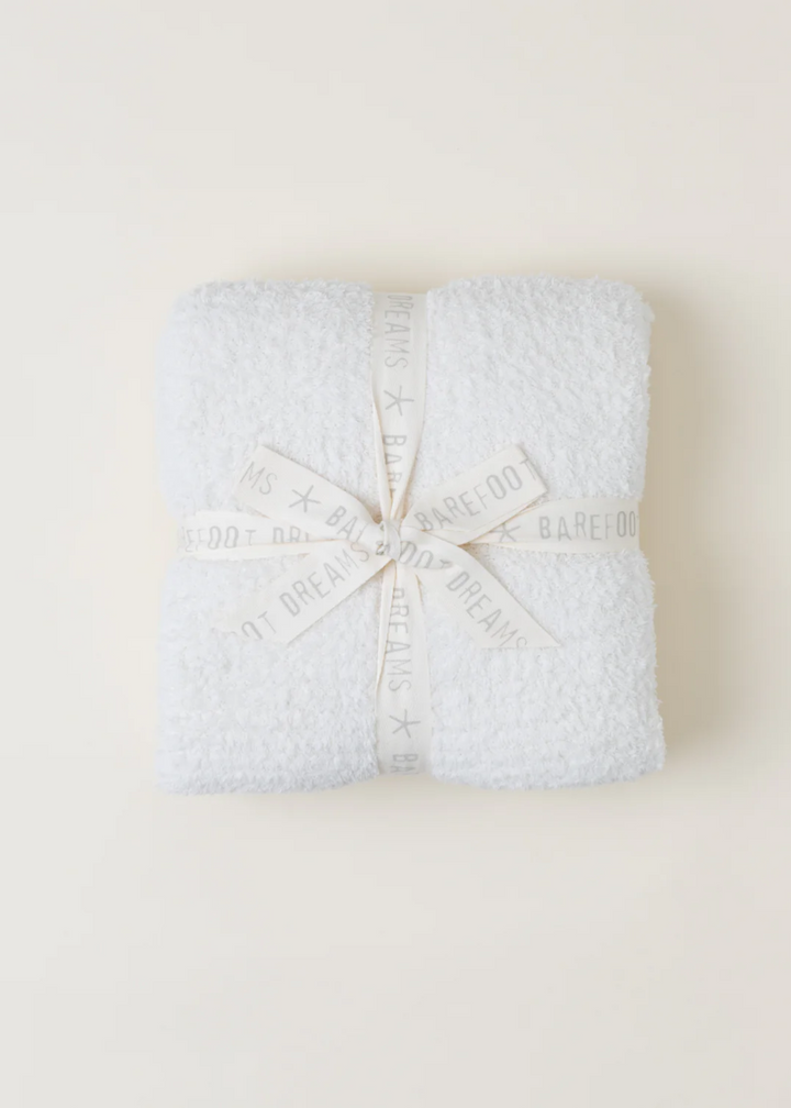 A cream blanket folded and laying on a white background