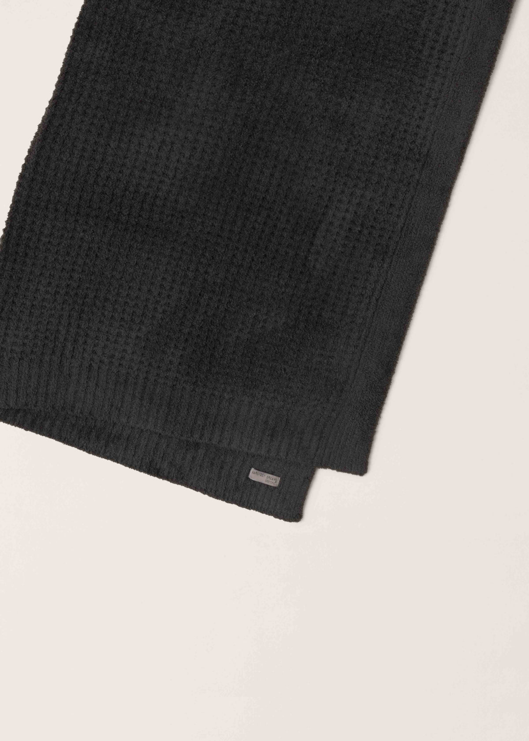 Dark grey waffle knit blanket folded in half laying on a white background