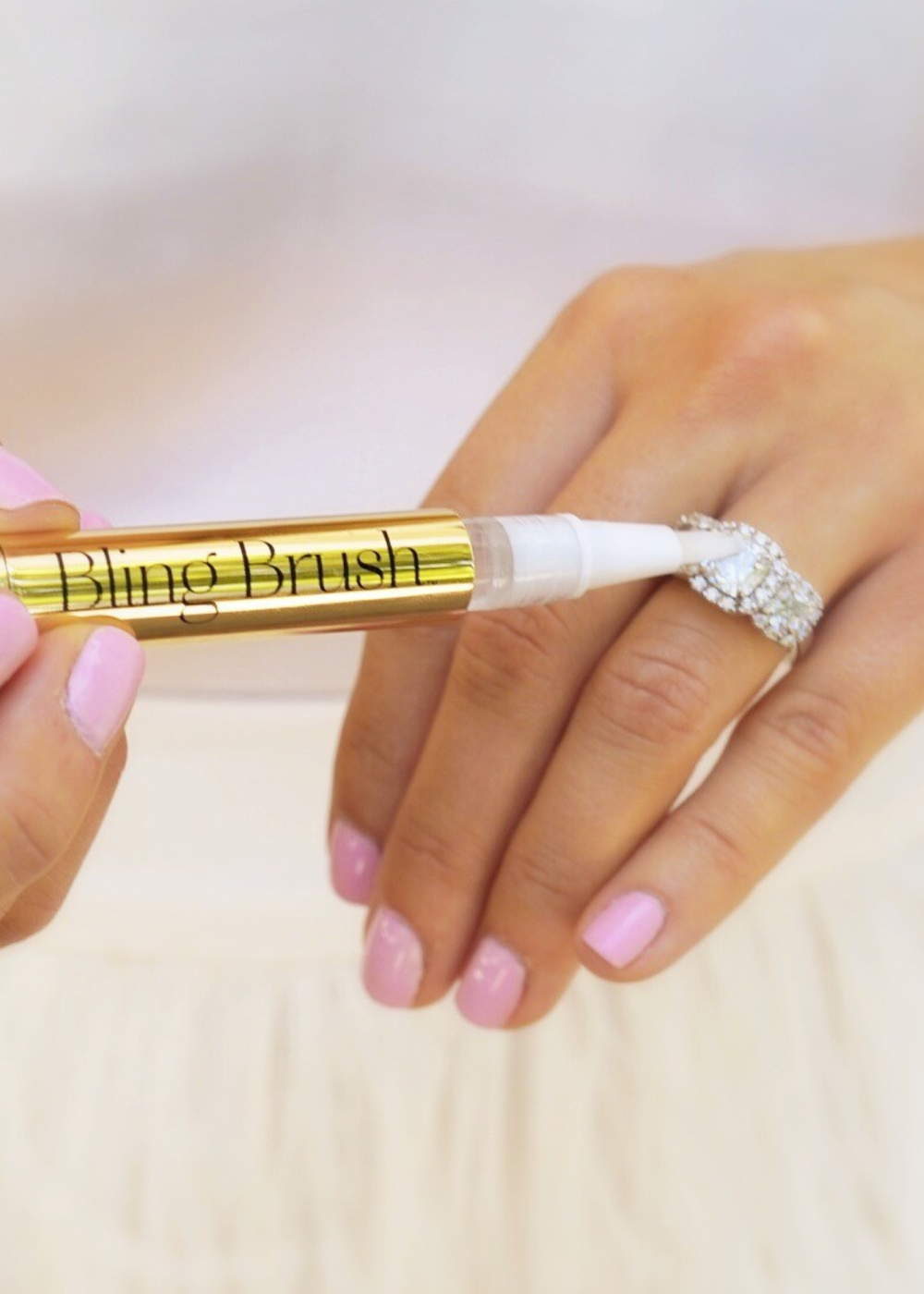 Woman cleaning a ring with a gold jewelry cleaning brush pen