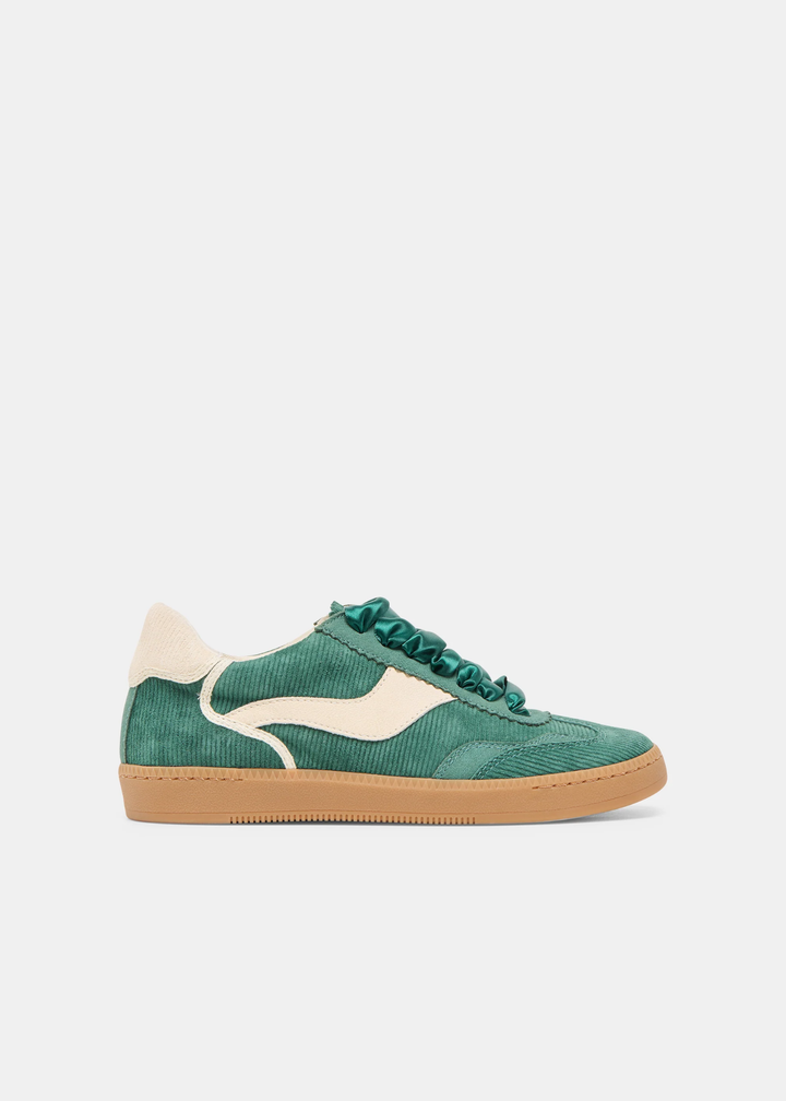 Women's green corduroy sneaker with white designs and a white heel and dark green silk shoe strings and a tan sole on against a white background