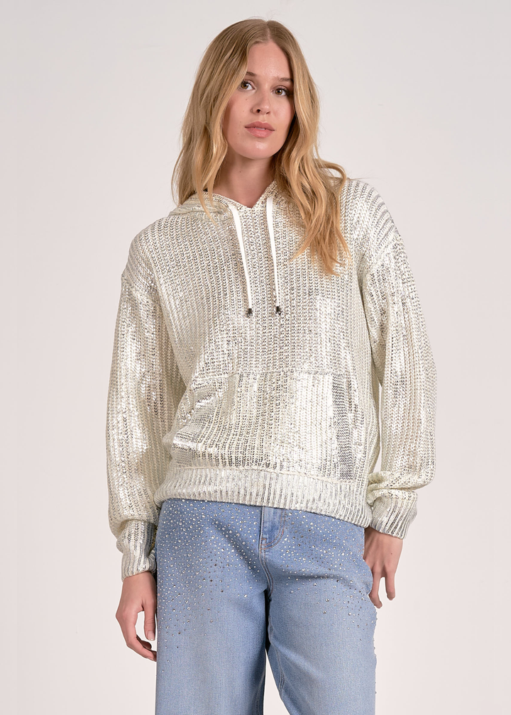 Woman wearing a white sequin hoodie with jeans against a white background