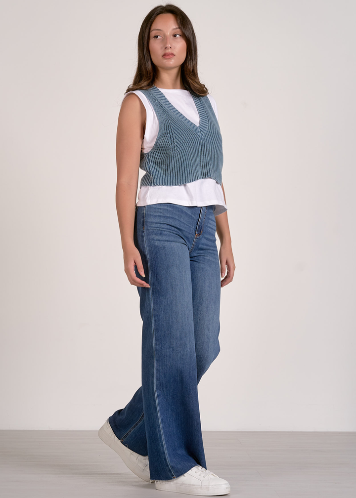 Woman wearing a blue and white layered top with jeans