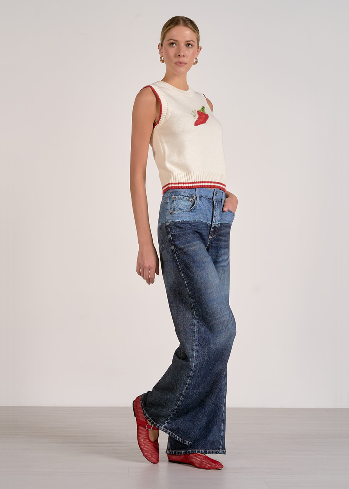Woman wearing a white sleeveless knit top with a red pepper and "chillin" graphic and jeans
