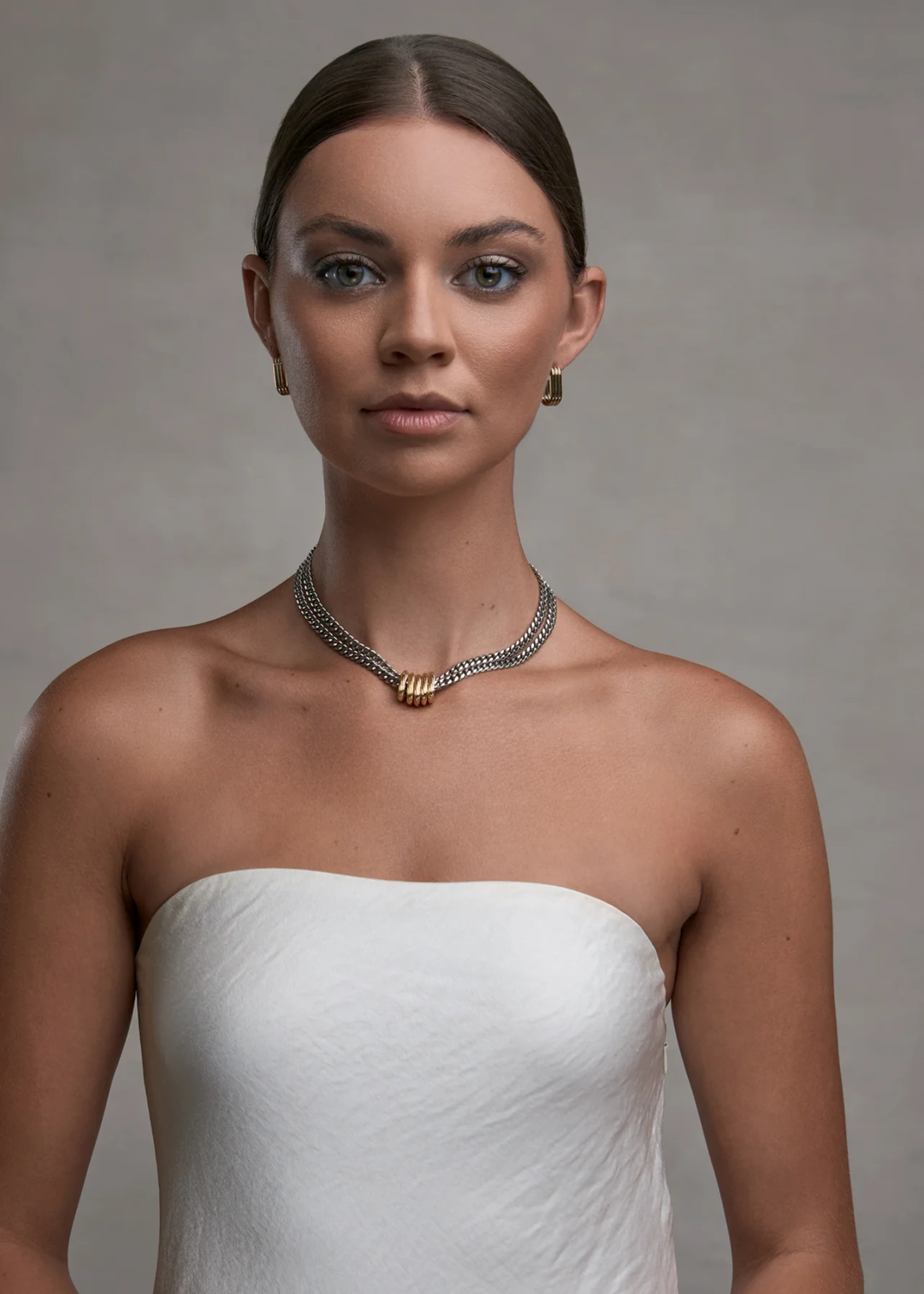 Woman wearing a silver double chain necklace with gold rings