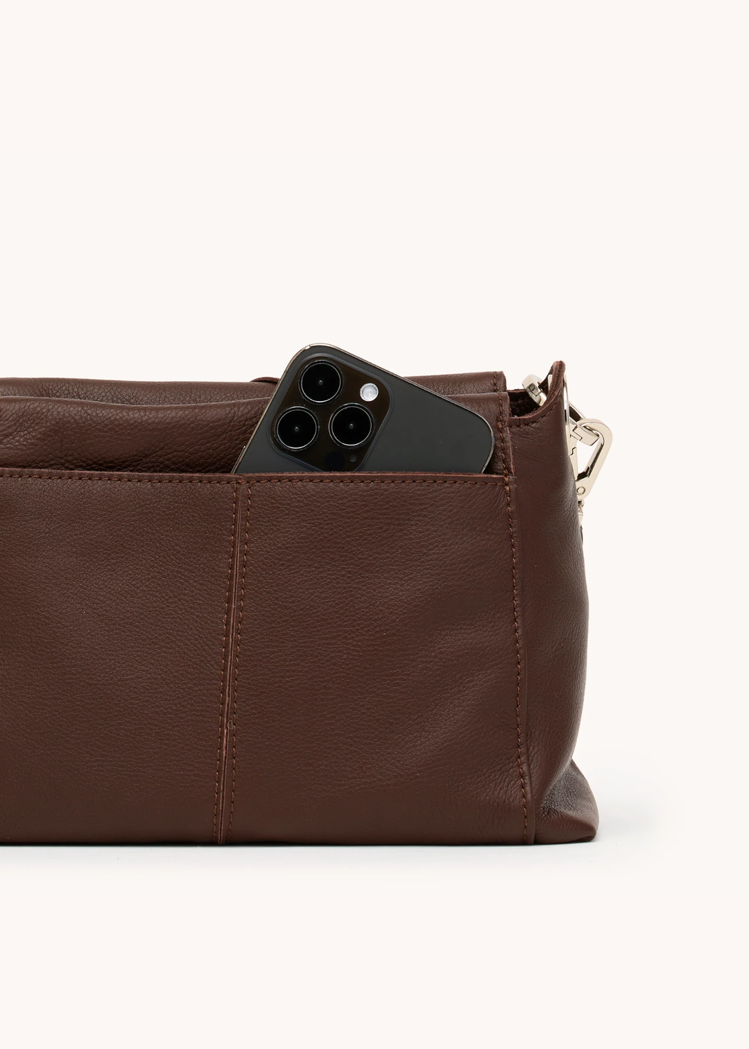 Brown leather woven purse with silver hardware on a white background with an iphone in the side pocket