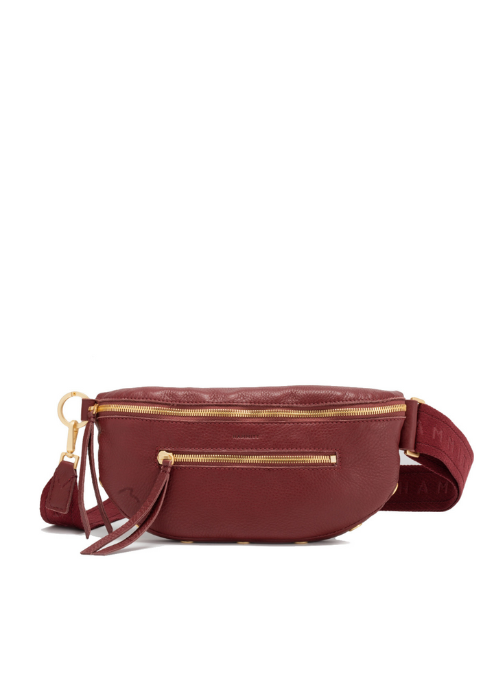 Red/brown crossbody bag with brushed gold zippers on a white background