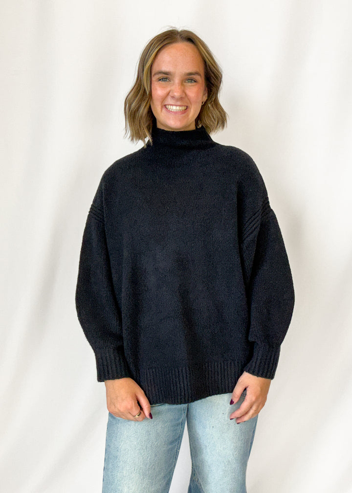 Woman wearing a black mock neck long sweater