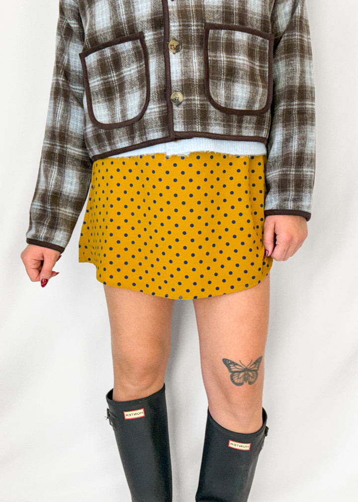Woman wearing a yellow and navy polka dot mini skirt