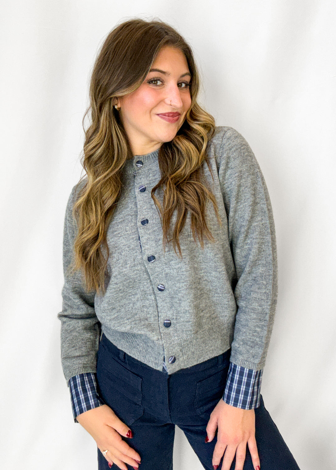 Woman wearing grey cardigan with bluie stripe cuff and button details