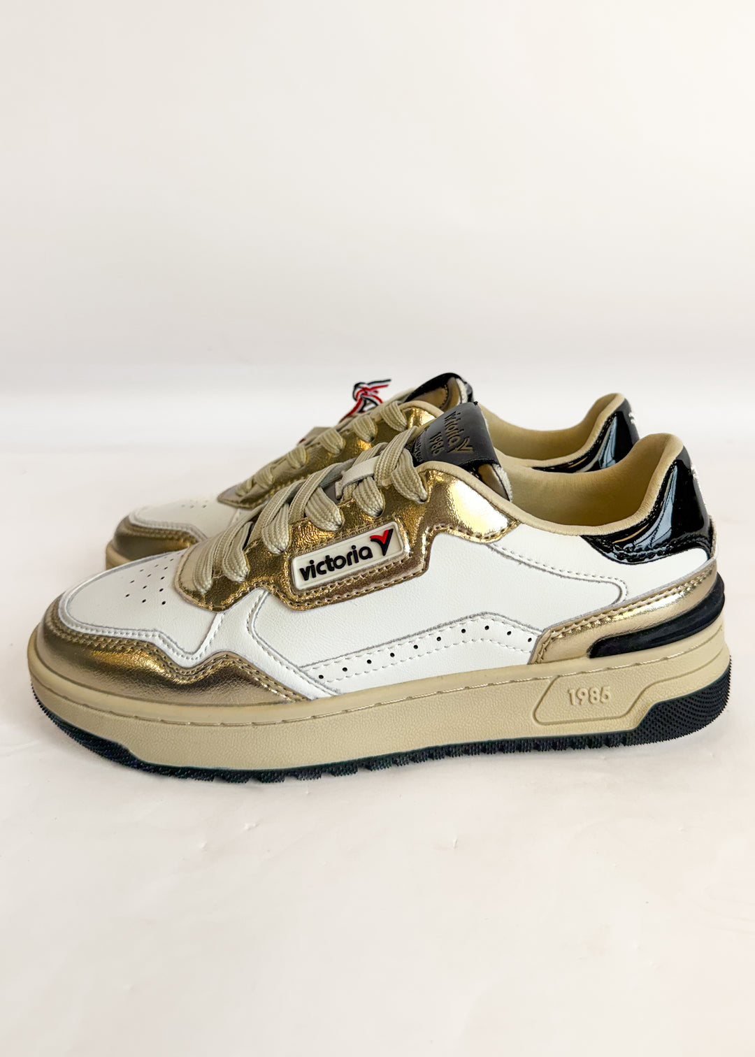 White and beige sneakers with a visible brand logo on a light gray background