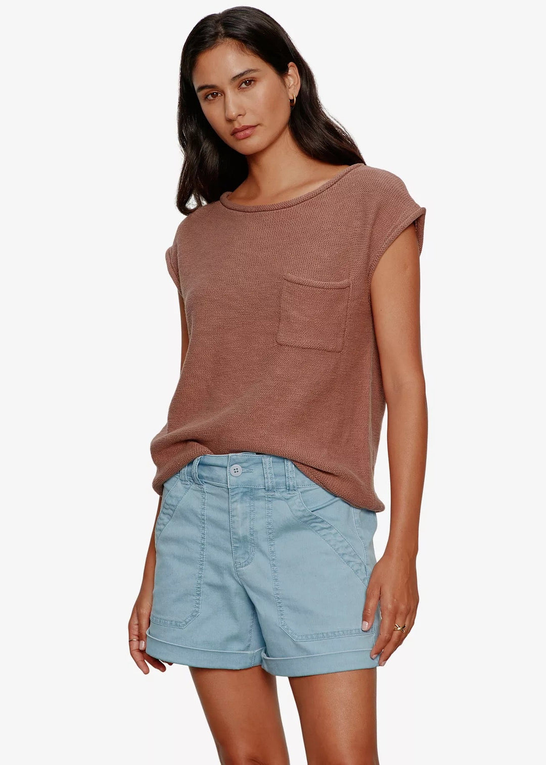 Woman wearing a brown sleeveless top and light blue shorts on a white background