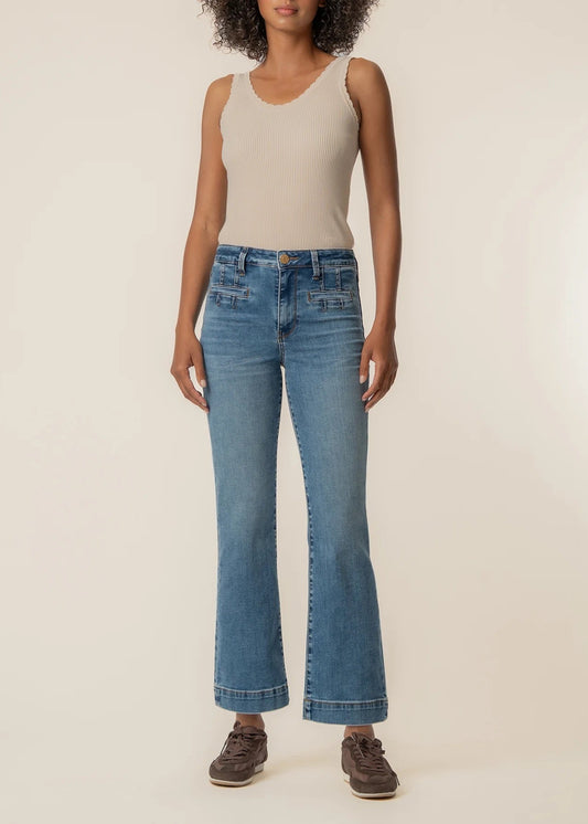 Person wearing blue jeans and a beige top on a plain background