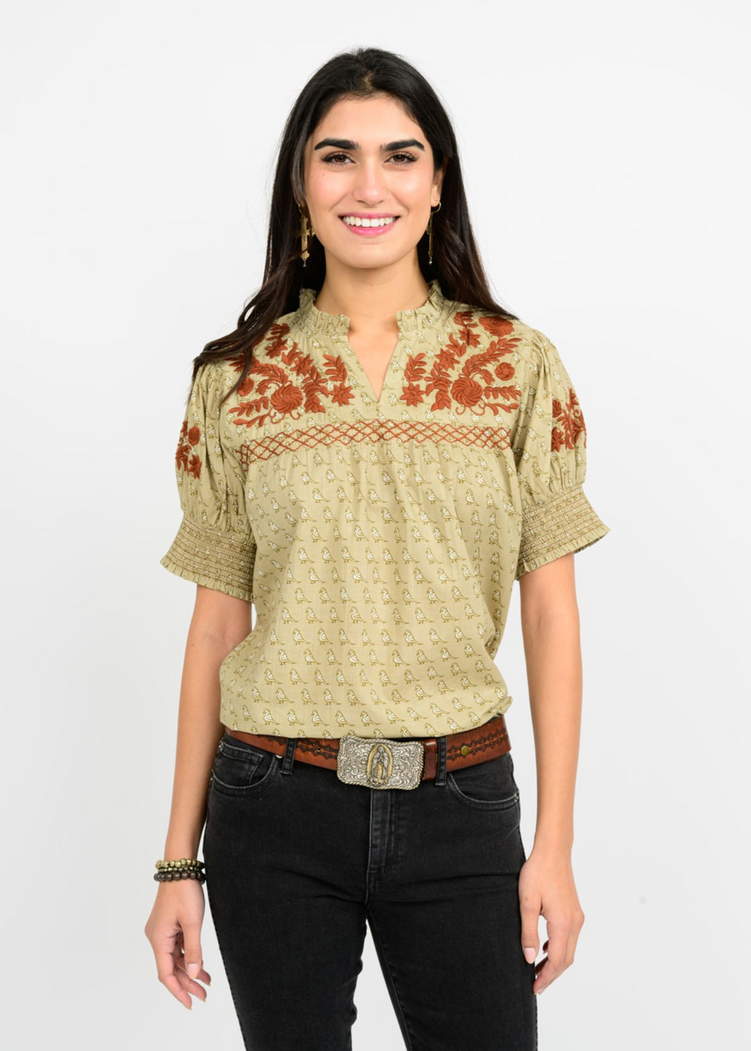 Woman wearing a green top with a small bird pattern and brown embroidery 