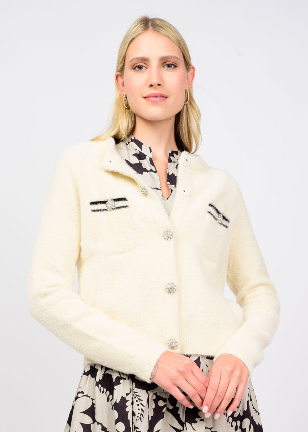 Woman wearing an ivory cardigan over a black and white dress