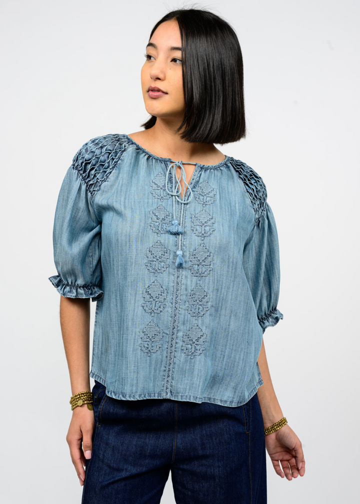 Woman wearing a blue denim top with embroidered details