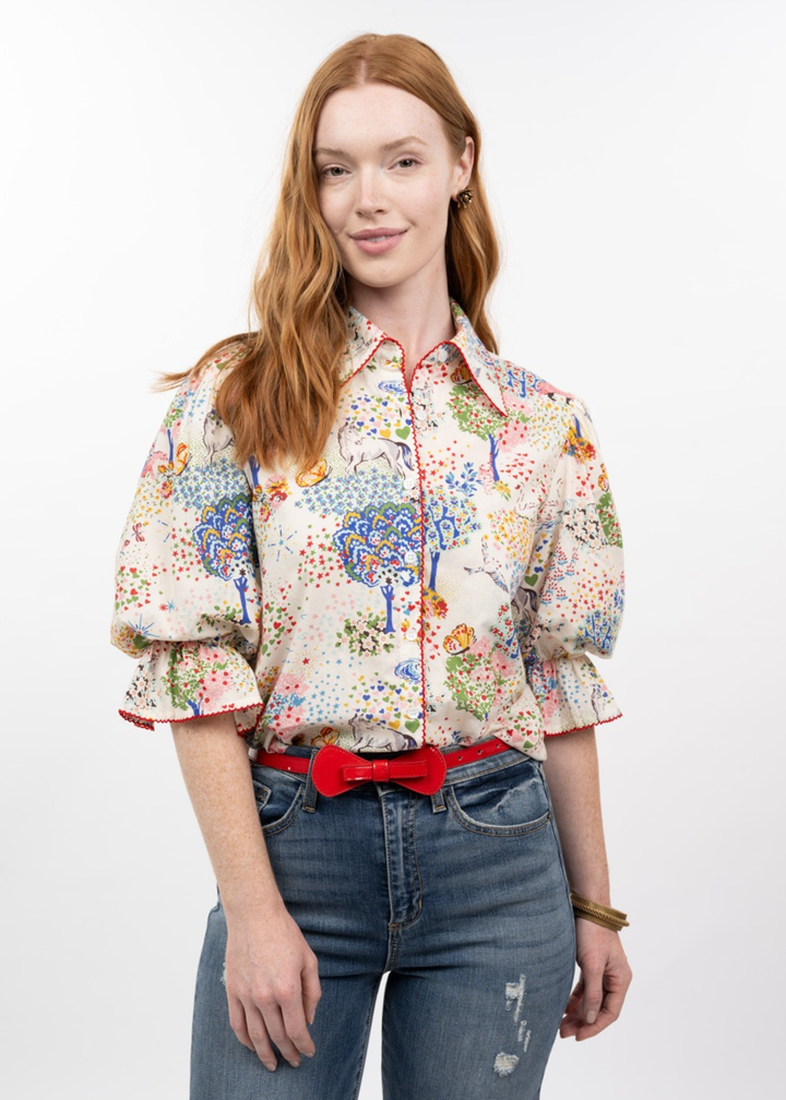Woman wearing a multicolor patterned button down top with puff sleeves and jeans