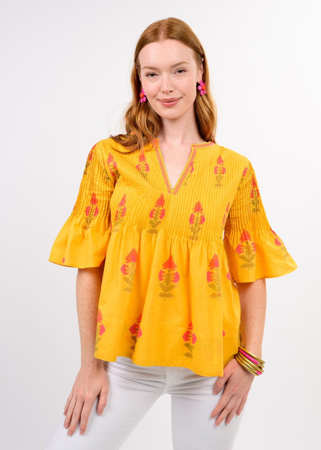Woman wearing a yellow v-neck top with a floral print and white jeans
