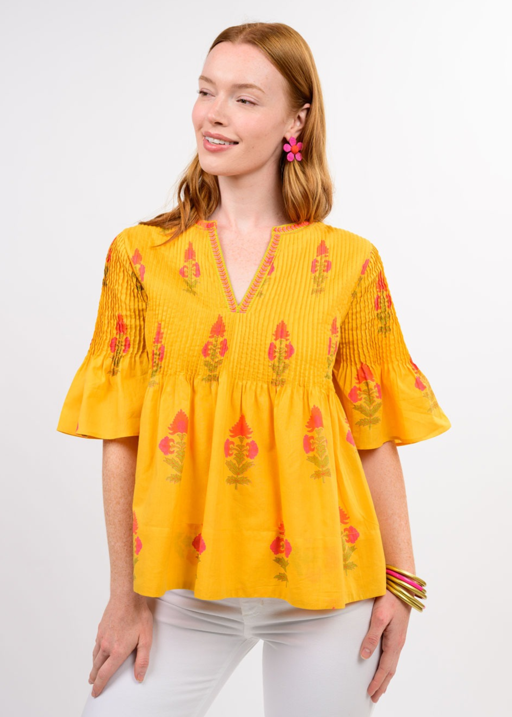 Woman wearing a yellow v-neck top with a floral print and white jeans