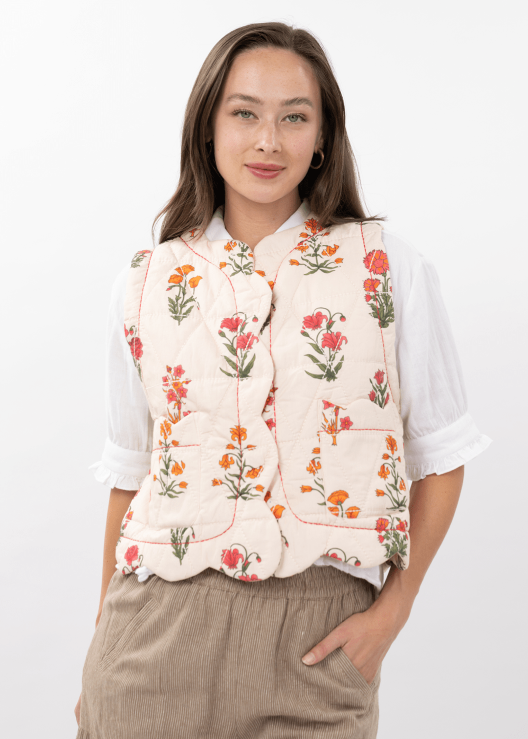 Woman wearing an ivory quilted floral vest with brown pants