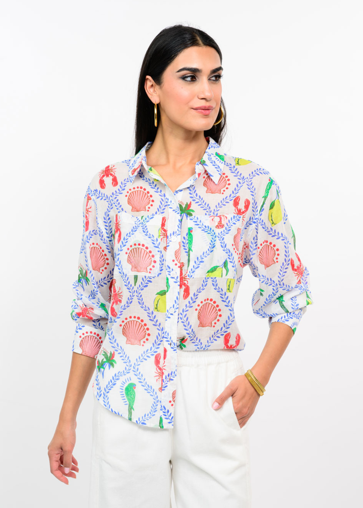Woman wearing a white button down with a multicolor pattern with white jeans