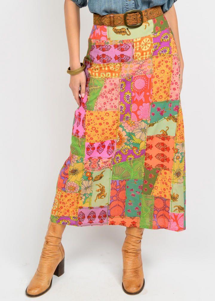 Woman wearing a bright, multicolored midi skirt with a various patterned patch design in front of a white background