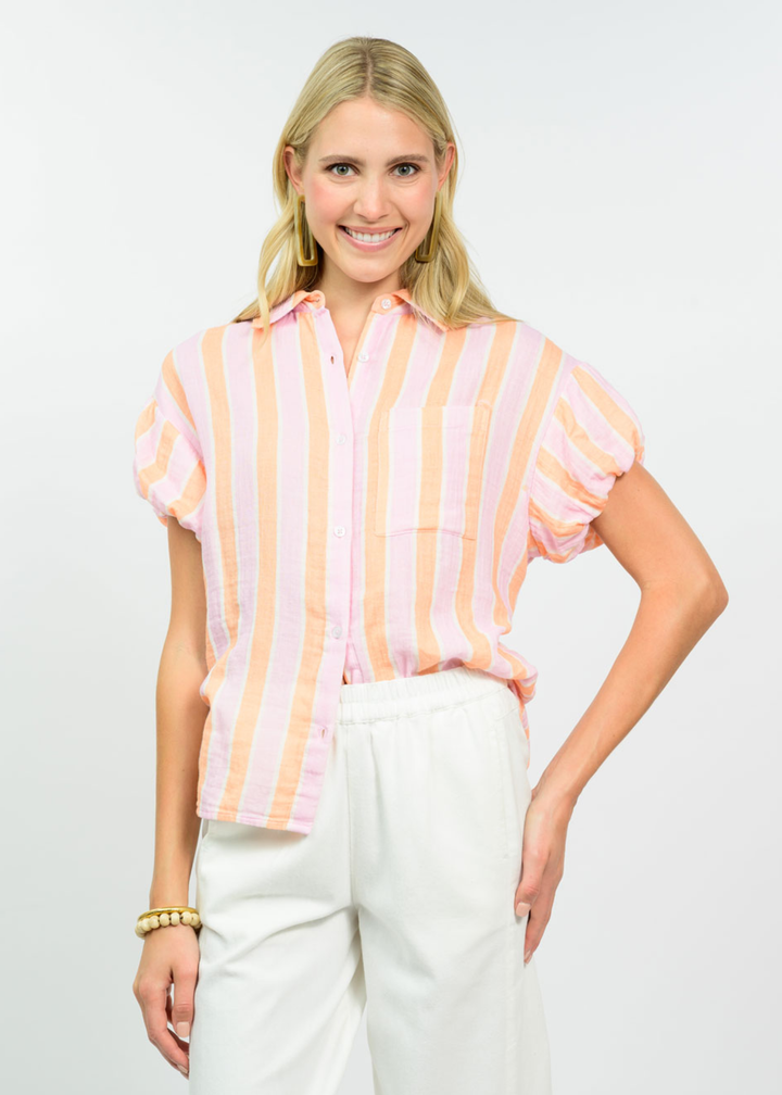Woman wearing a tangerine striped collared button down with white pants