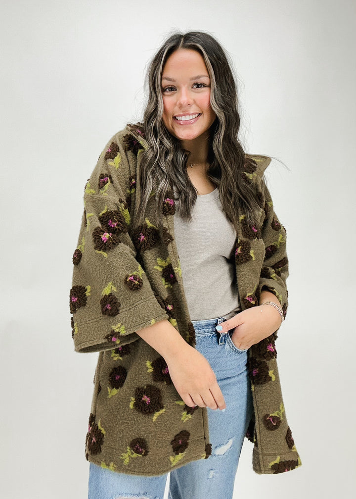 A woman wearing a brown Ivy Jane floral embroidered jacket with 3/4 sleeves, styled with a tank top and distressed jeans for a casual and stylish look.