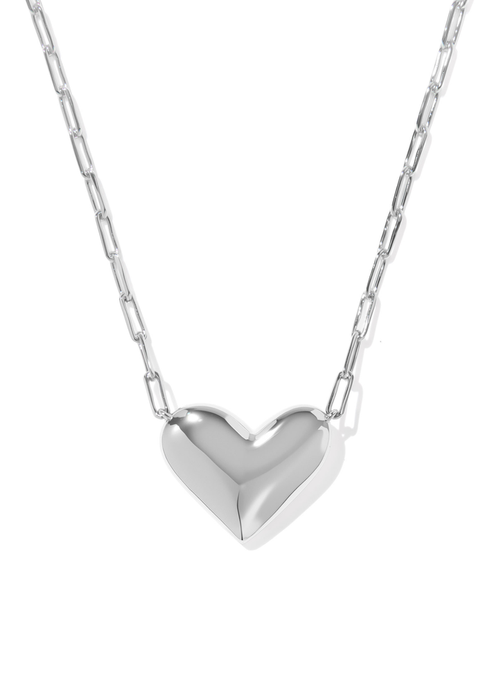 A silver necklace with a silver heart shaped pendant against a white background